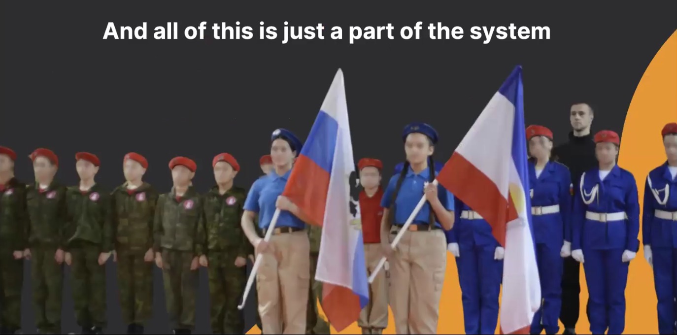 A group of children and teenagers stand in a line wearing various militarized uniforms, including the red berets of Yunarmiya, camouflage fatigues, and blue cadet uniforms. Two children in the center hold large flags, including the Russian tricolor. The text above them reads: "And all of this is just a part of the system."