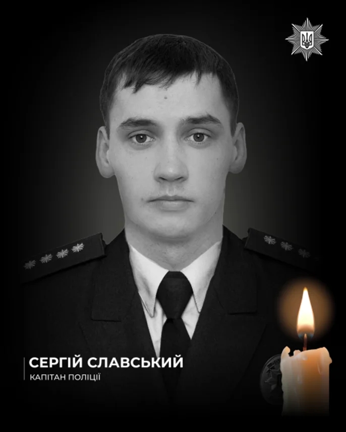 A black and white commemorative portrait shows Captain Serhiy Slavskyi in a formal police uniform from the Sumy Oblast, Ukraine. A lit candle is positioned in the bottom-right corner, and the National Police of Ukraine logo appears in the top-right corner.