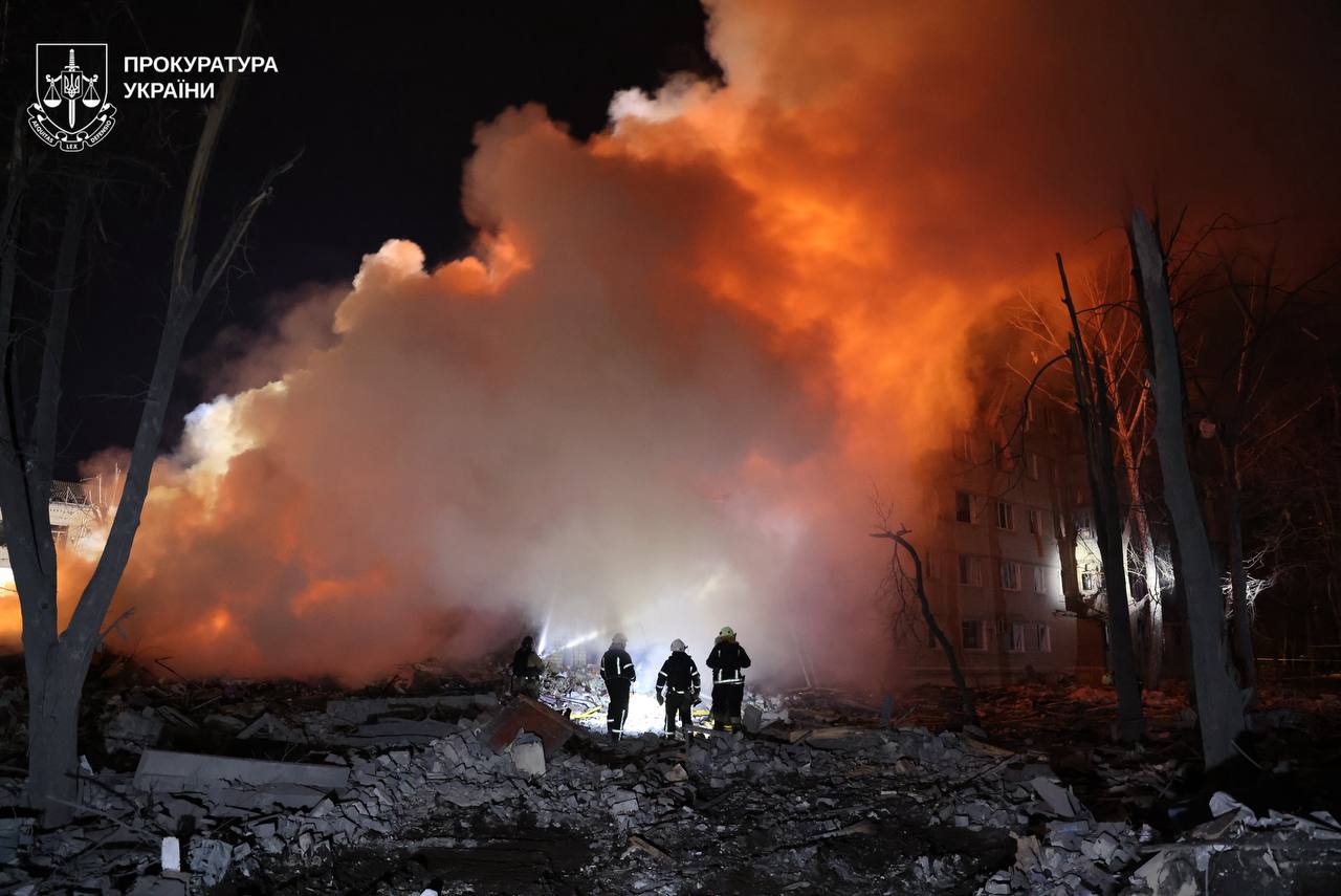 Alt-text Generator
Custom Gem
Alt-text Generator said
A multistory brick apartment building stands heavily damaged with blown-out windows and destroyed balconies, while smoke and a small fire rise from a pile of rubble in the foreground. The National Police of Ukraine logo is positioned in the bottom right corner.

Thick smoke and orange flames erupt from a partially collapsed apartment building at night as firefighters work near a large pile of debris. A ladder leans against the damaged facade, and the Kharkiv Regional Military Administration logo appears in the bottom right.

A complex flight path map shows numerous curved yellow and colored lines tracking aerial targets across Ukraine from launch points in Russia, Belarus, and occupied territories. The infographic includes a legend for various missile and drone types and covers the period from March 6 to March 7, 2026.

The charred and mangled remains of a vehicle sit on a dirt road, with the hood propped open to reveal a destroyed engine compartment and the tires burned down to the rims. A logo for the Sumy Regional Military Administration is visible in the upper left corner.

A silver sedan parked in a dirt lot has its rear passenger-side windows shattered and the door frame dented, with the National Police of Ukraine logo visible in the bottom right corner.

Firefighters stand before a massive wall of glowing orange smoke and fire rising from a debris field at night. The Prosecutor General of Ukraine logo is located in the upper left corner.