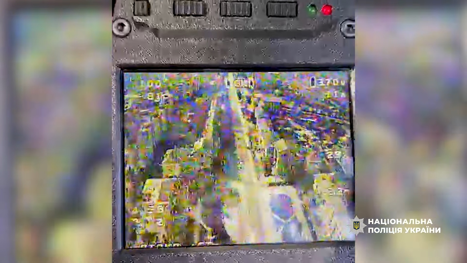 A distorted, low-resolution screen displays a high-angle aerial view of a road and buildings, likely from a drone's camera feed, with various telemetry data overlays. The National Police of Ukraine logo is visible in the bottom right corner.