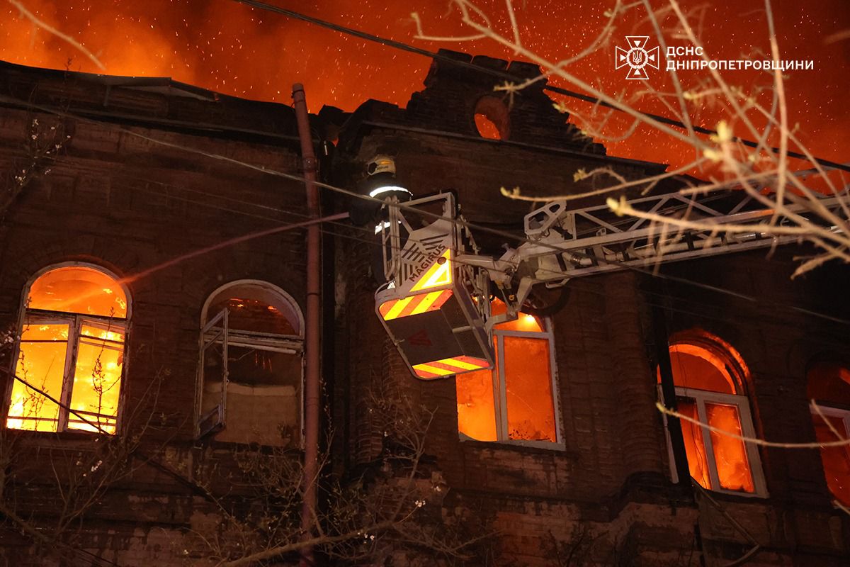 Alt-text Generator
Custom Gem
Firefighters in Dnipropetrovsk Oblast use a mechanical lift to reach the upper windows of a historic building engulfed in flames at night. Intense orange light and sparks fill the sky above the structure, while the State Emergency Service of Ukraine (DSNS) logo is visible in the upper-right corner.